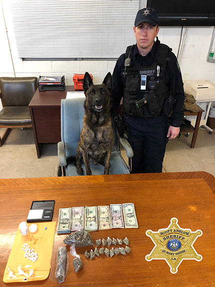 an Officer with their K-9 Unit before their recovered drugs and money