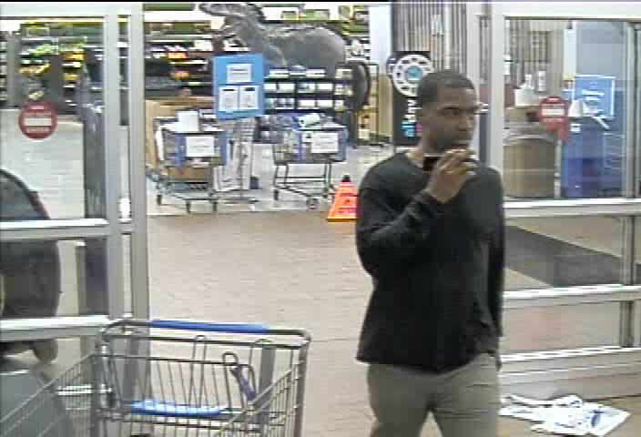 black male in black long sleeve shirt with tan pants, talking on cell phone - Suspect 2