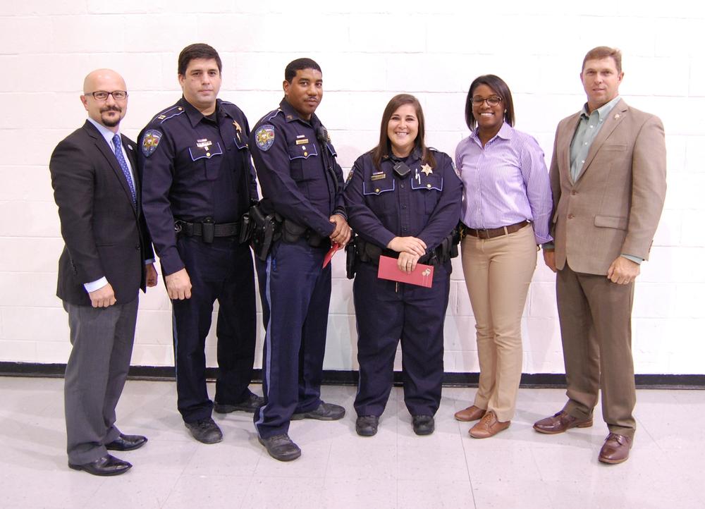 6 people standing and smiling in suits and uniforms