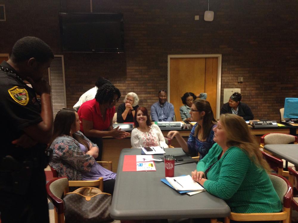 Several women sitting at a table talking to two officers