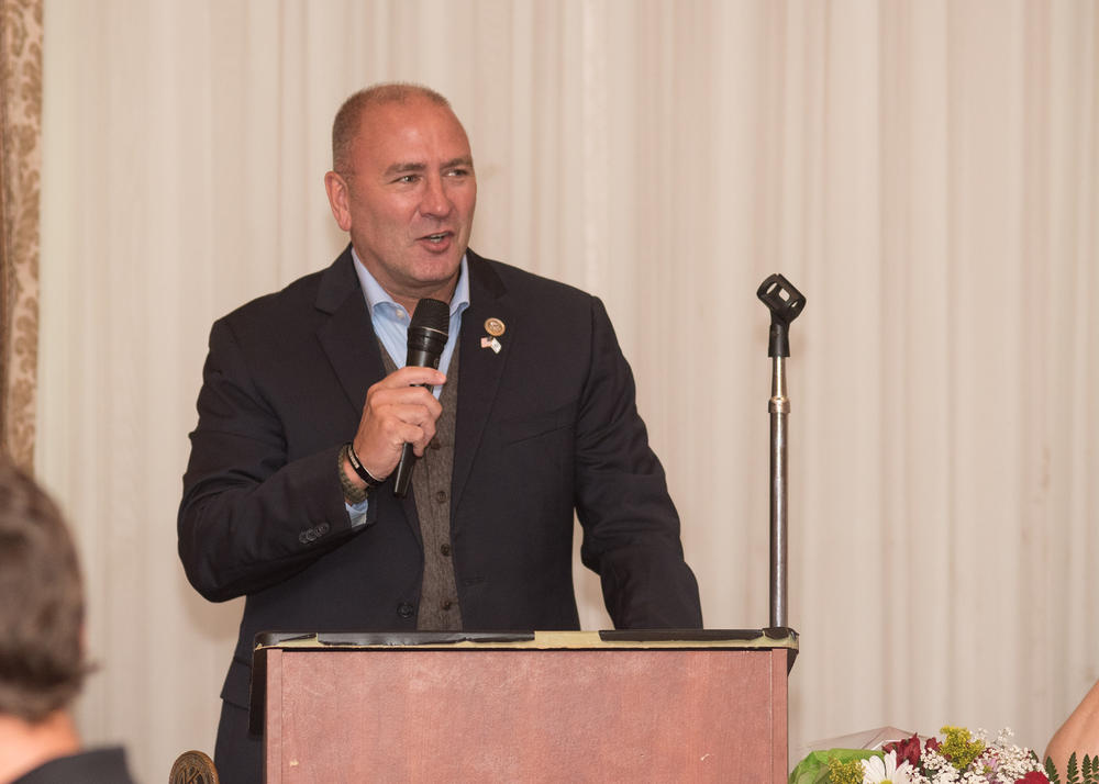 Congressman Clay Higgins holding a microphone, giving a speech