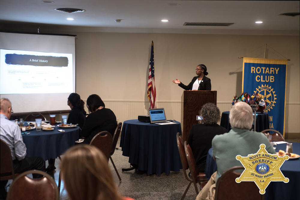 An officer giving a presentation, gesturing to a presentation.