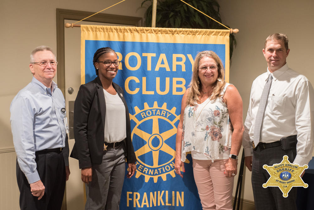 Four officers standing in front of the Rotary Club Banner